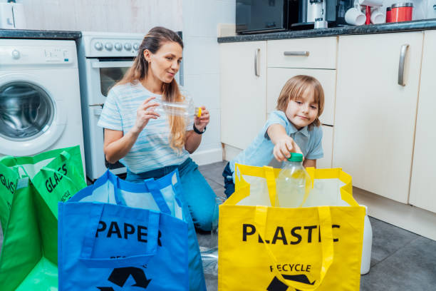 istock Mother is teaching kid how to recycle help the boy aware environmental importance - mom educates son sort garbage into different bins on kitchen. Family sorting garbage at home. Concept of recycling. 2063221369