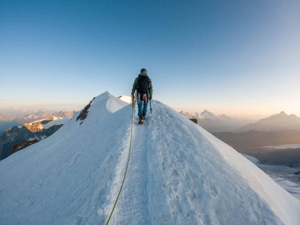 Alpinist aiming for the summit on snowy ridge An intrepid alpinist ascends a snowy ridge with unwavering determination, pushing towards the summit in the pristine and challenging terrain of high-altitude adventure. reach destination stock pictures, royalty-free photos & images