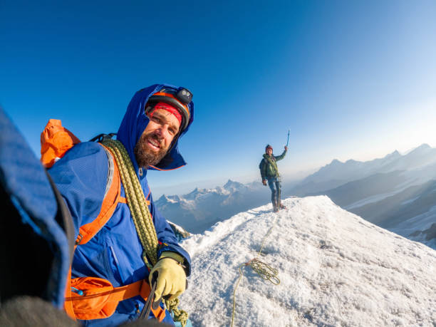 A jubilant team of mountaineers reaches the summit of a towering mountain in the Swiss Alps, capturing the victorious moment with a shared selfie that immortalizes their collective achievement and camaraderie amidst the breathtaking alpine panorama.