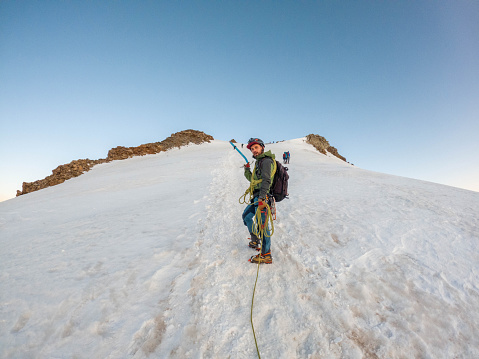 An intrepid alpinist ascends a snowy ridge with unwavering determination, pushing towards the summit in the pristine and challenging terrain of high-altitude adventure.
