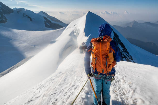 An intrepid alpinist ascends a snowy ridge with unwavering determination, pushing towards the summit in the pristine and challenging terrain of high-altitude adventure.