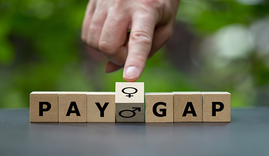 Wooden cubes form the expression 'pay gap'.