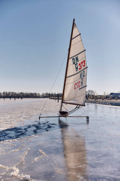 Ice sailing on the Braassemermeer near Roelofarendsveen in the municipality of Kaag en Braassem mede Veendermolen on a sunny day. It is mid-February 2021 in the Netherlands, people are skating and ice sailing on a large lake.