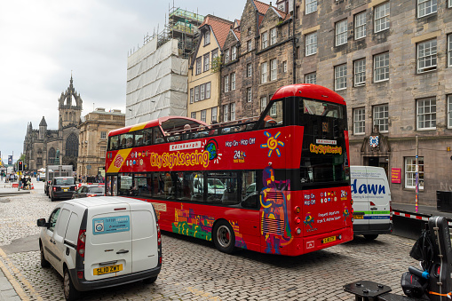 Royal Mile, Edinburgh, Scotland, August 2023. This is the Royal Mile early morning during the Edinburgh Fringe Festival.  There are tourists on an open topped bus.