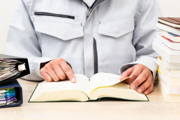 A woman wearing work clothes looking up a dictionary
