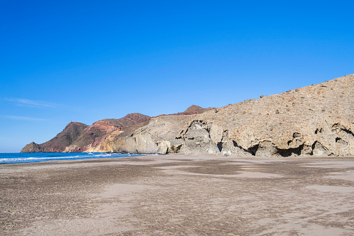 Cala de Mónsul, a beautiful dark sand beach lapped by crystal water, one of the landmarks of the nature park