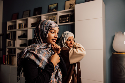 Two muslim sister getting dressed wearing a hijab at home.
