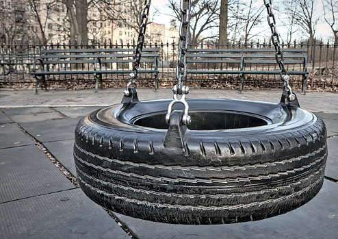 tire swing on metal chains in a public park (mount prospect park brooklyn new york city) urban playground, rubber mat flooring for kids, benches,   infrastructure, recreation rope