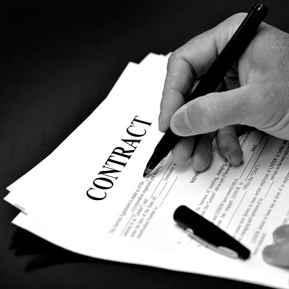 Contract on desk with black pen being signed by person