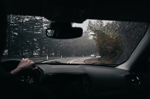 Driving a car in rainy weather on country road.