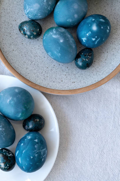 istock Blue spotted naturally colored Easter eggs on plates, on white tabletop background, flat lay, top view 2063363382