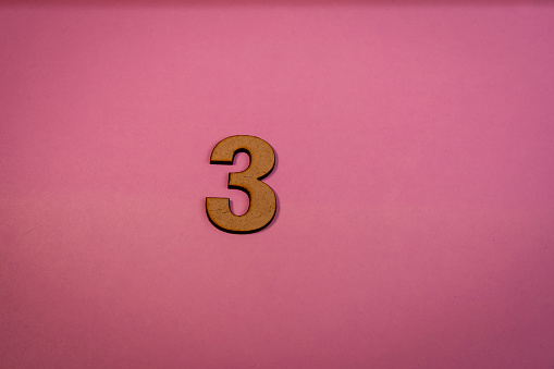 Number 3 in wood on a pink background