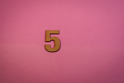 Number 5 in wood on a pink background