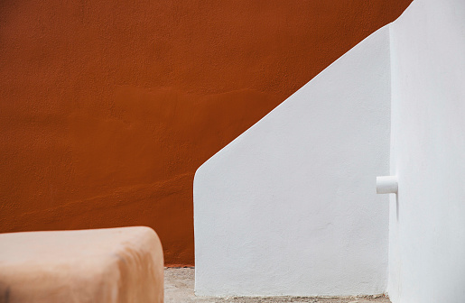 A striking contrast of earthy red and crisp white walls, showcasing the minimalist beauty of Aegean architectural design.