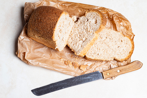 High angle view of wholemeal bread with knife over paper bag