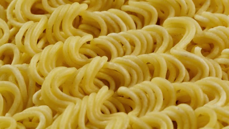 Close-up of instant noodles texture. Asian fast food with meat and spices. Instant noodles, or instant ramen, is a type of food consisting of noodles sold in a precooked and dried block with flavouring powder and seasoning oil. Cooking or soaking in