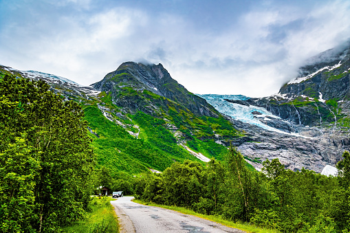 The largest glacier in continental Europe, Jostedalsbreen, is located in the mountains. The wet road winds through a narrow hollow. Jostedalsbreen Park.