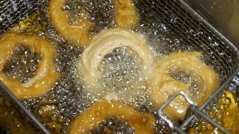 Deep-fried onion rings in a hot pan with oil boiling.