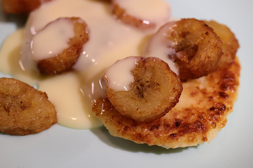 Fried cheesecakes sprinkled with condensed milk and grilled bananas. Yummy background.
