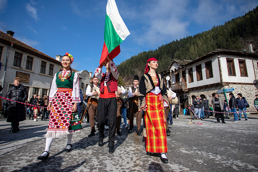 Shiroka Laka, Bulgaria - March 03, 2024: Women and men dressed in Bulgarian national costumes open the Pesponedelnik Masquerade Games Festival in Shiroka Laka, Bulgaria