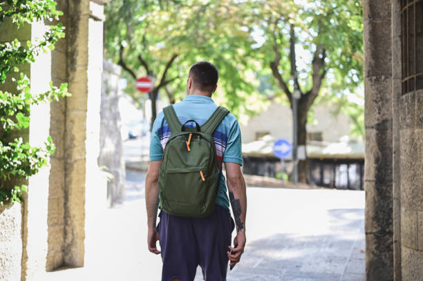 istock handsome hipster man walking in street with backpack. 2063434997