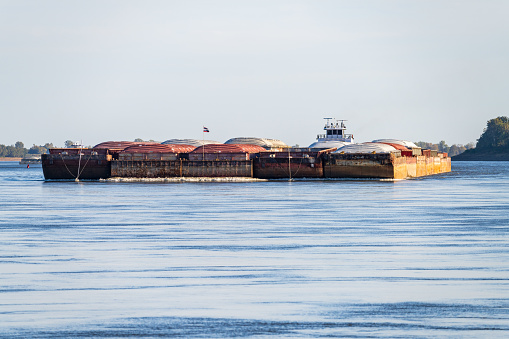 Freight barges approaching over the calm waters of the Mississippi river during low water conditions