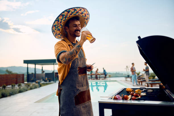 istock Happy man drinking beer while grilling food on a barbecue. 2063453076