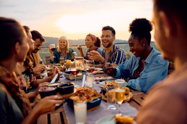 istock Happy man talking to his friends at dining table on a terrace at sunset. 2063455268