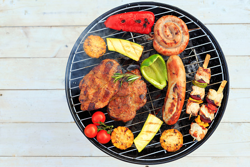 Grill with glowing charcoal briquettes on a red, white and blue rustic wood theme for the patriotic holidays of Fourth of July, Memorial Day and Labor Day traditional picnics.