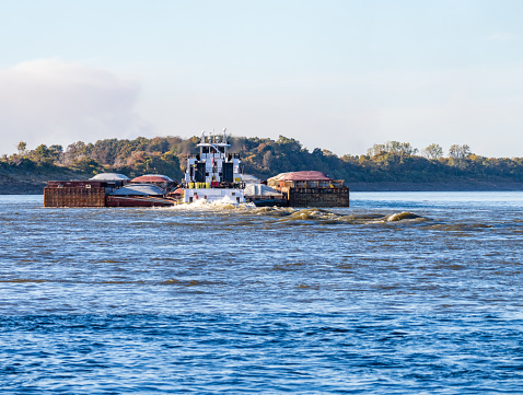 Freight barges moving over the calm waters of the Mississippi river during low water conditions