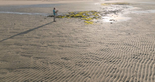 istock Aerial view of photographer exploring tidal pools 2063511674