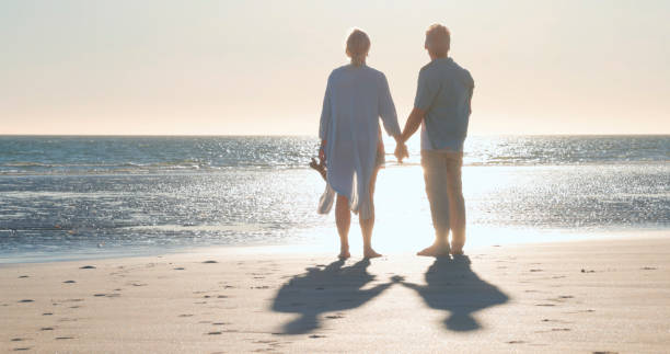 istock Mature couple walk along empty beach, hold hands 2063518265
