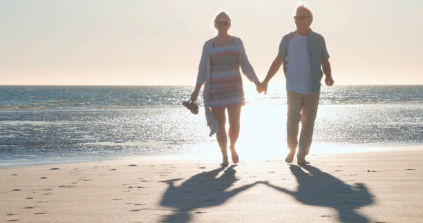 istock Mature couple walk along empty beach, hold hands 2063518266