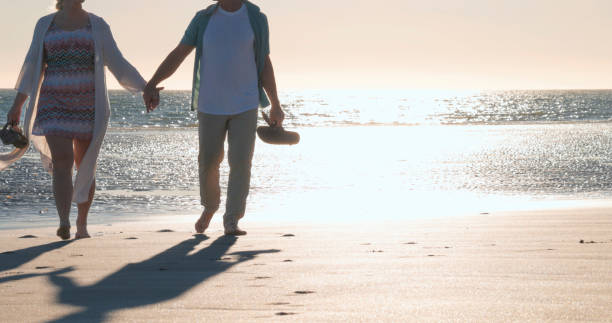 istock Mature couple walk along empty beach, hold hands 2063518268