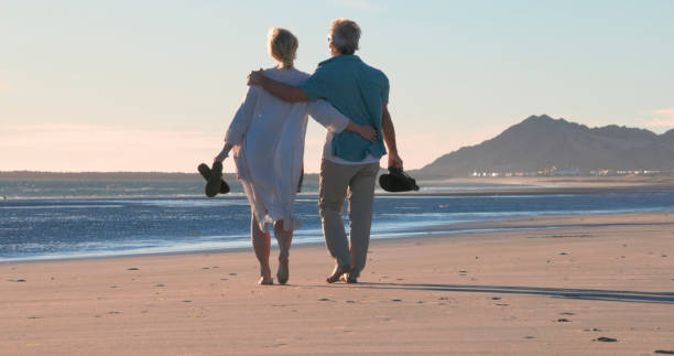 istock Mature couple walk along empty beach, hold hands 2063520417