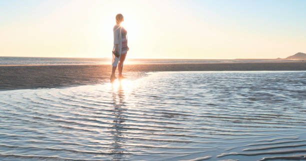 istock Mature woman pauses on empty beach 2063520423