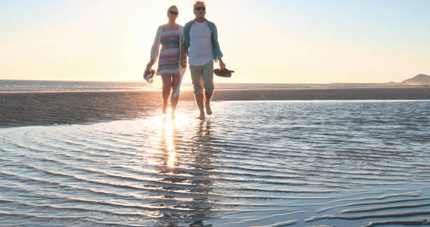 istock Mature couple walk along empty beach, hold hands 2063520939