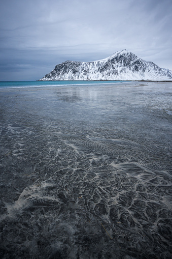 Interesting patterns and textures left by fading ebbs on the Skagsanden beach with the Hustind mountain at the background