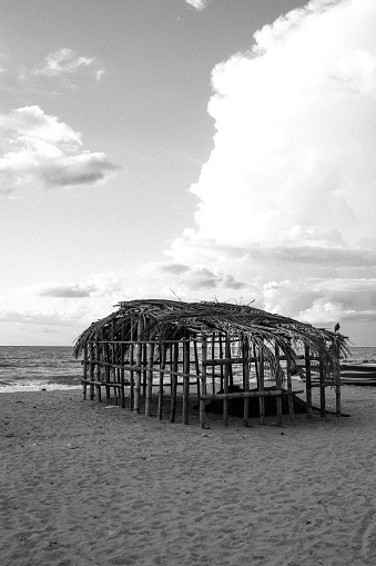 A black-and-white photo of a fisherman's hut made of sticks on the sandy shore of the Indian Ocean in Negombo, Sri Lanka