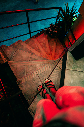 The photo captures feet in slippers ascending illuminated stairs bathed in red light in Negombo, Sri Lanka. The warm glow creates a mysterious and atmospheric ambiance