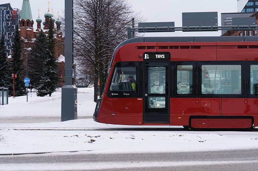 Red Tram car Travelling Down Snow Covered Street on Tampere, Finland. January 27, 2024.