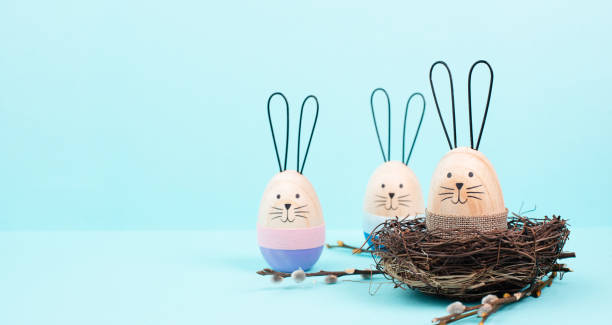istock Easter bunny or rabbit sitting in a bird nest, willow branches, wooden egg, spring holiday, blue color 2063576455
