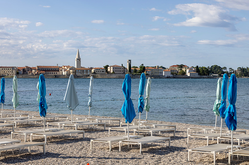 Porec, Croatia, Istria - September 30, 2023: View from the beach with umbrellas and sun loungers of the city with the bell tower of the Basilica of Euphrasius