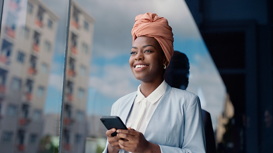 Black business woman, phone and street with smile for texting, thinking or communication on web. Person, employee and outdoor in city by buildings with smartphone for mobile app, chat or social media