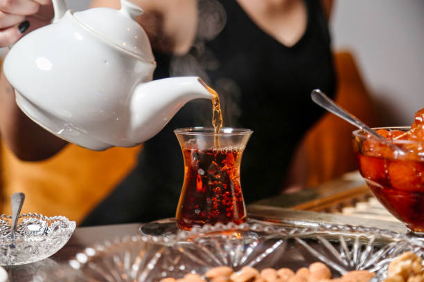 istock Woman Pouring Tea Into Glass Teapot 2063607327