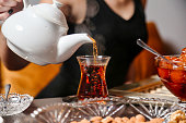 Woman Pouring Tea Into Glass Teapot