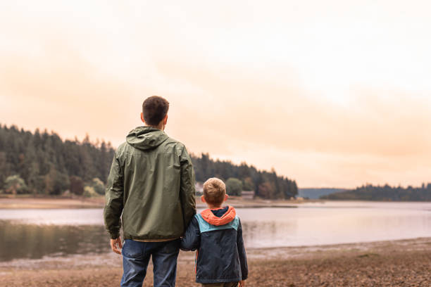 istock Father and son watching beautiful sunset by the lake. 2063615798