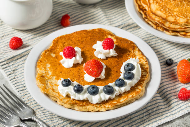 Sweet American Smiley Face Breakfast Pancakes with Whipped Cream and Berries