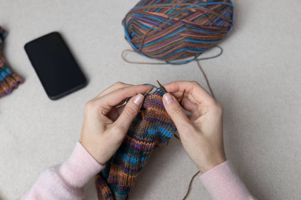 female hands knitting on knitting needles. Handmade colorful wool socks.