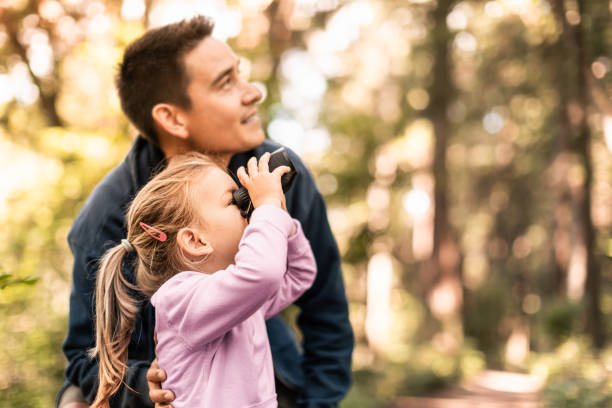 istock Father and daughter looking for birds with binoculars in the forest. 2063631335